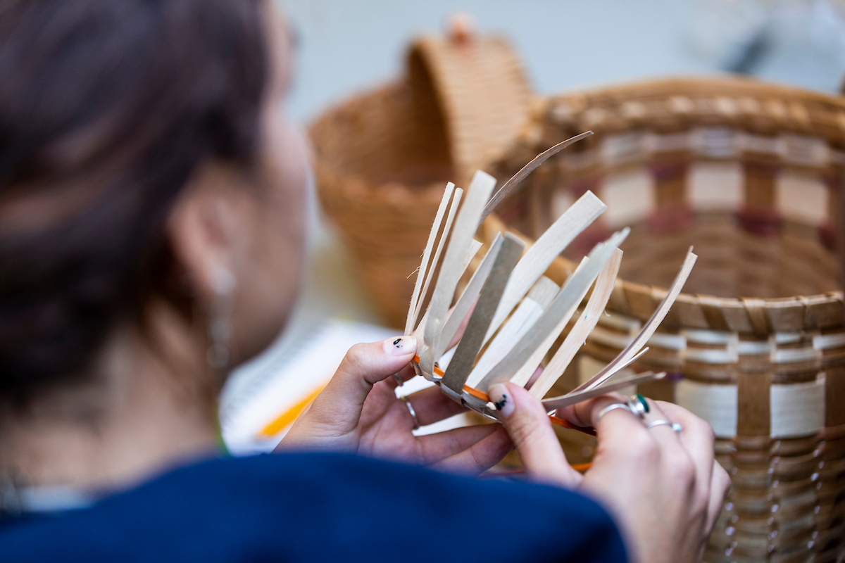 A person makes a handmade basket.